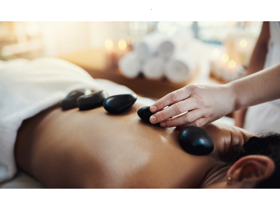 A person receiving a stone massage with hot stones on their back.